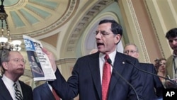 Sen. John Barrasso [C] quotes a USA Today article about gas prices as he and Sen. Lamar Alexander [L] and Senate Republican leader Mitch McConnell [R] speak to reporters, at the Capitol in Washington, D.C., May 17, 2011