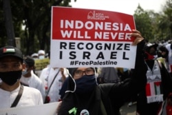 Seorang perempuan Muslim memegang poster saat demonstrasi menentang serangan Israel di Gaza, di luar Kedutaan Besar AS di Jakarta, Jumat, 21 Mei 2021. (Foto: AP)