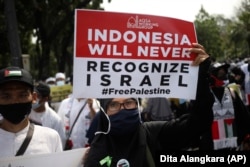Seorang perempuan Muslim memegang poster saat demonstrasi menentang serangan Israel di Gaza, di luar Kedutaan Besar AS di Jakarta, Jumat, 21 Mei 2021. (Foto: AP)