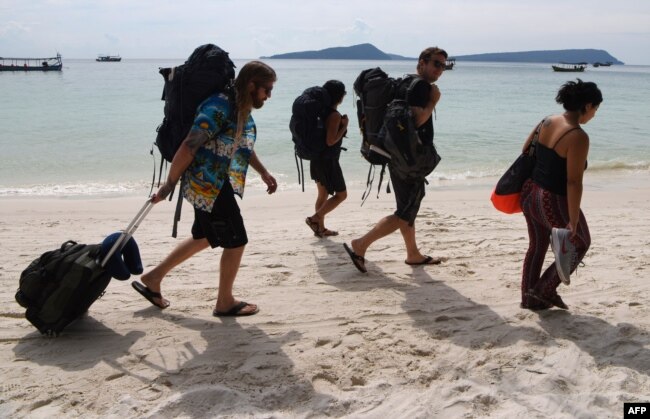 FILE - Tourists walk along a beach on Koh Rong island in Sihanoukville province on October 31, 2019. (Photo by TANG CHHIN Sothy / AFP)
