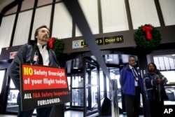 Federal Aviation Administration employee Michael Jessie, who is currently working without pay as an aviation safety inspector for New York international field office overseeing foreign air carriers, holds a sign while attending a news conference at Newark Liberty International Airport, Jan. 8, 2019, in Newark, New Jersey.