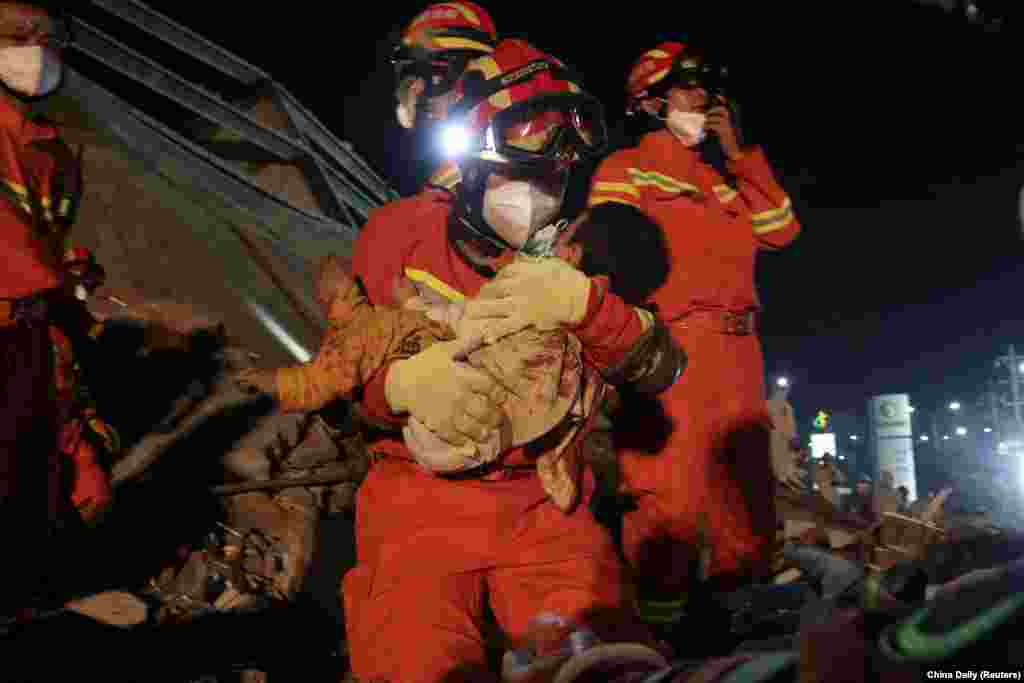 A worker wearing a face mask rescues a child at the site where a hotel being used for the coronavirus quarantine collapsed, in the southeast Chinese port city of Quanzhou, Fujian province.