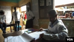 Un officier observateur dans un bureau de vote à Conakry, inspectant une liste d'électeurs lors de l'élection présidentielle en Guinée, le 11 octobre, 2015. (Photo: C. Stein)