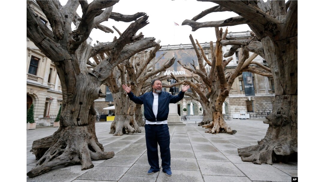 FILE - Chinese artist Ai Weiwei poses for photographers with one of his pieces at his exhibition at the Royal Academy of Arts in London, Sept. 15, 2015.