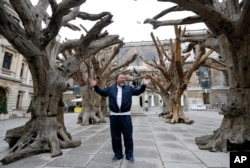 FILE - Chinese artist Ai Weiwei poses for photographers with one of his pieces at his exhibition at the Royal Academy of Arts in London, Sept. 15, 2015.