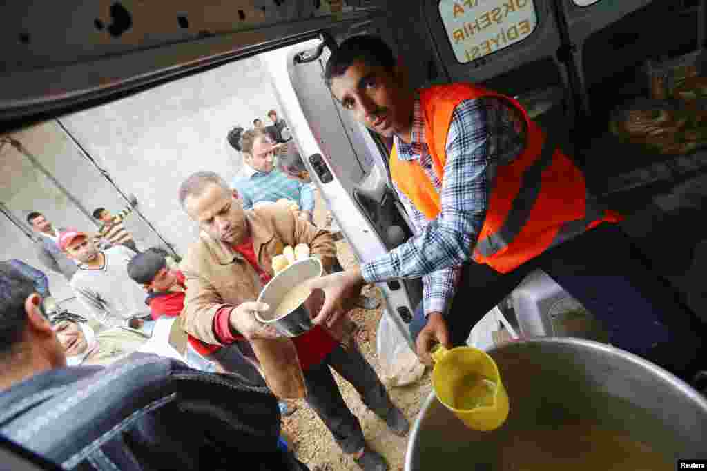 A Turkish aid worker distributes food to refugees from Kobani, Syria now living in a refugee camp in Suruc, Turkey, Oct. 16, 2014. 