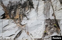 Workers known as "Tecchiaioli" examine marble at the Cervaiole quarry on Monte Altissimo in the Apuan Alps, Tuscany, Italy, July 18, 2017.