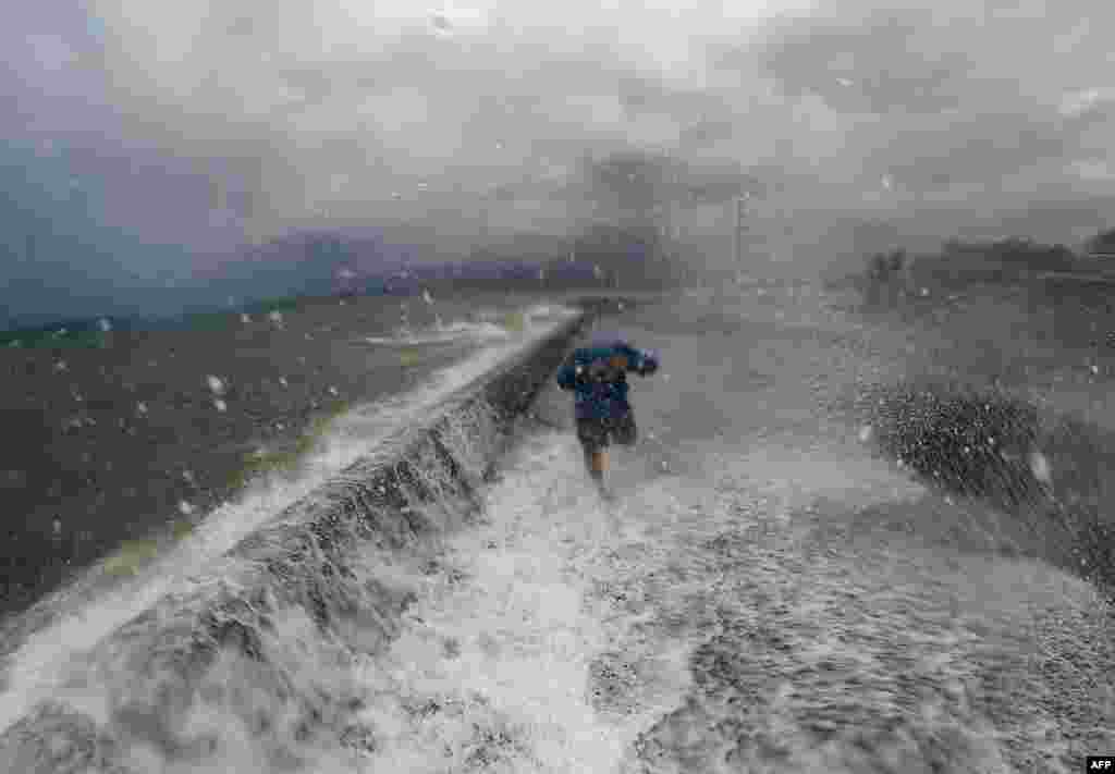 A resident walks past big waves spilling over a wall onto a coastal road in the city of Legaspi in Albay province, south of Manila, as typhoon Melor approaches the city. More than 700,000 people fled the central Philippines amid threats of giant waves, floods and landslides as powerful Typhoon Melor approached the archipelago nation, officials said.