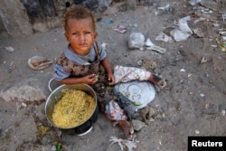 FILE - A girl displaced by the war in the northwestern areas of Yemen eats outside her family's makeshift hut on a street in the Red Sea port city of Hodeida, Yemen, Dec. 25, 2017.