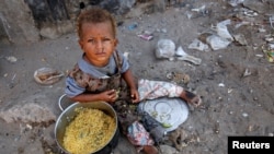 FILE - A girl displaced by the war in the northwestern areas of Yemen eats outside her family's makeshift hut on a street in the Red Sea port city of Hodeida, Yemen, Dec. 25, 2017.