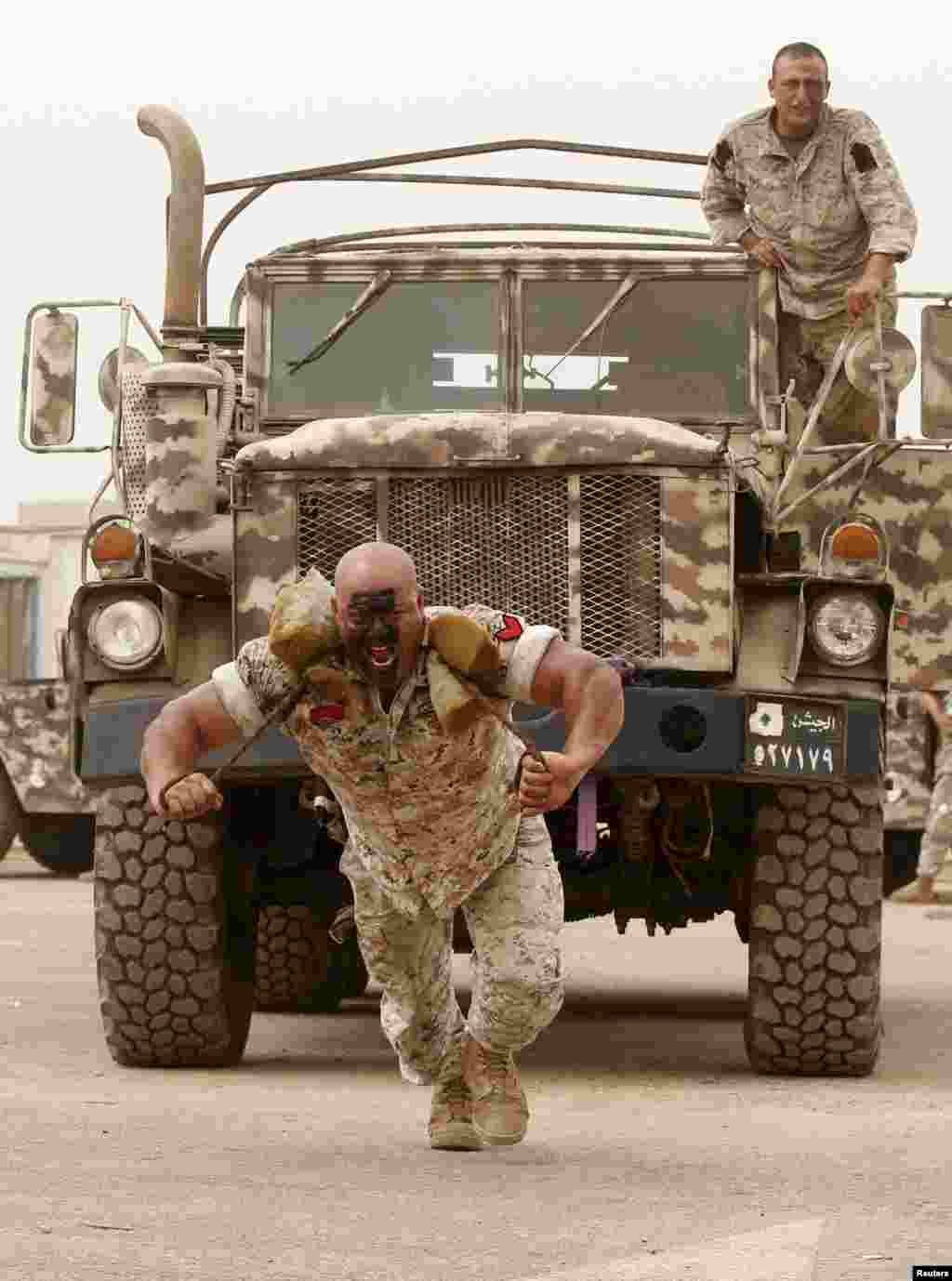 A member of the Lebanese Army's airborne regiment pulls an army truck during a live drill during the Security Middle East Show in Beirut.