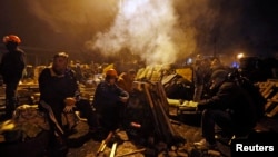 Anti-government protesters rest next to a barricade in Independence Square in Kyiv, Ukraine, Feb. 21, 2014.