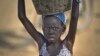 FILE - A young displaced girl carries a bucket of water back to her makeshift shelter at a United Nations compound which has become home to thousands of people displaced by the recent fighting, in the Jebel area on the outskirts of Juba, South Sudan, Dec. 31, 2013.