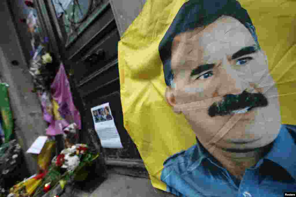 A flag with a portrait of jailed Kurdistan Workers Party (PKK) leader Abdullah Ocalan is seen in front of the entrance of the Kurdistan Information Center in Paris, where three female Kurdish activists were found shot dead Thursday.