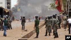 FILE - Guinea security forces, center, face people rioting and burning rubbish and other goods in the streets of Conakry, April 13, 2015.