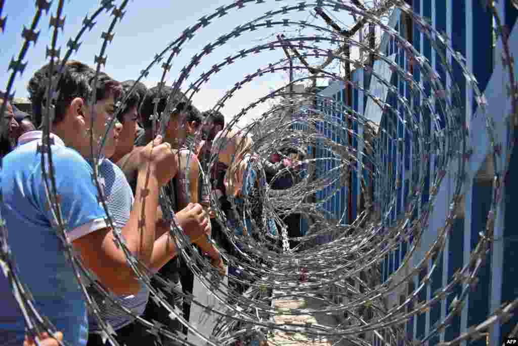 Displaced youths from Daraa province clutch a barbed-wire fence on the Syria-Israel border near the Syrian village of al-Rafid during a demonstration against the regime and calling for international protection.