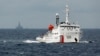 一艘中國海警船在南中國海上的一座中國海上鑽井平台旁駛過。（2014年6月13日）