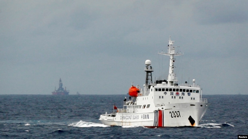 资料照：一艘中国海警船在南中国海上的一座中国海上钻井平台旁驶过。（2014年6月13日）(photo:VOA)