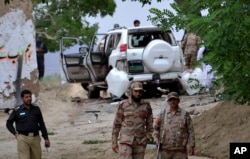 FILE - Pakistani security officials stand guard at the site of a suicide bombing which killed dozens of people and left many injured in Mastung district near Quetta, Pakistan, May 12, 2017.