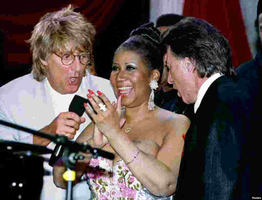 Rock star Rod Stewart (L) and actor Dustin Hoffman (R) join music legend Aretha Franklin on stage for a song during a show being taped in New York April 27, 1993.