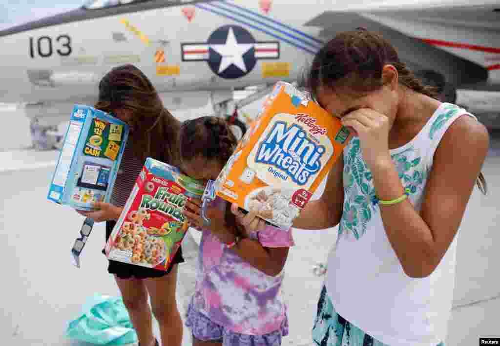 Michelle Campano (Right) and her sisters Jennifer (Middle) and Lauren Campano, all of Rockville, Maryland, check on the position of the sun using homemade solar viewers from the flight deck of the Naval museum ship U.S.S. Yorktown during the Great American Eclipse in Mount Pleasant, South Carolina, Aug. 21, 2017.