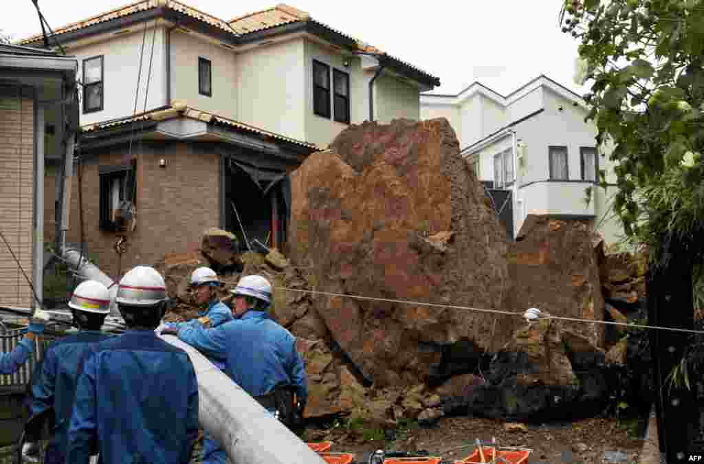 Sebuah rumah rusak dan tiang listrik ambruk akibat tertimpa batu-batu besar dari sebuah lereng runtuh setelah hujan deras akibat topan Wipha di Kamakura, pinggiran kota Tokyo.