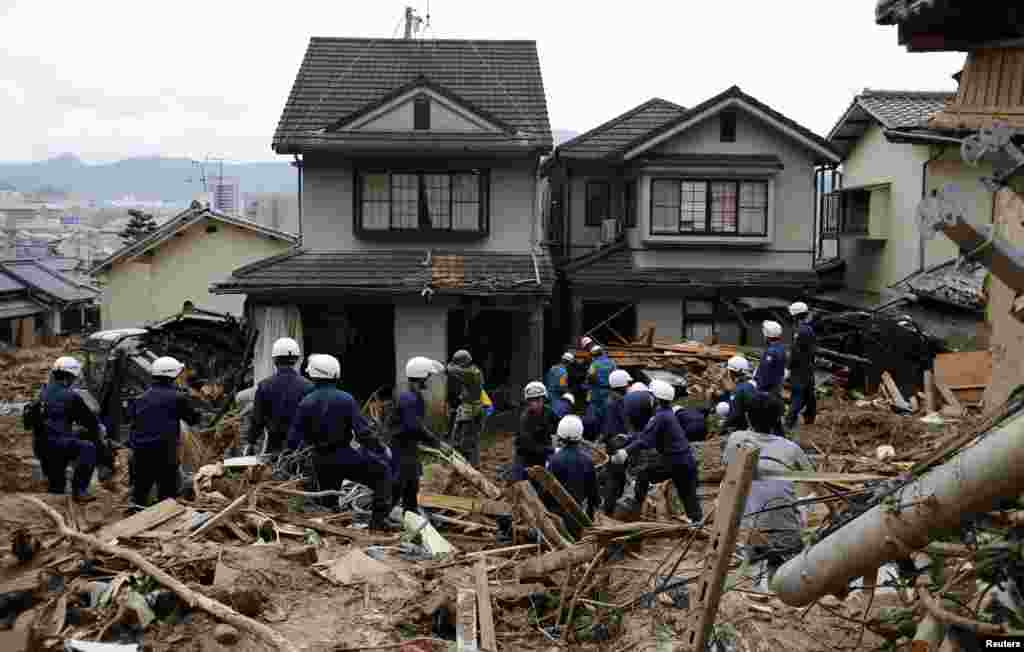 Police officers search for survivors at a site where a landslide swept through a residential area at Asaminami ward in Hiroshima, western Japan.&nbsp; Heavy rain delayed a search on Friday for more than 50 people believed buried under the debris.