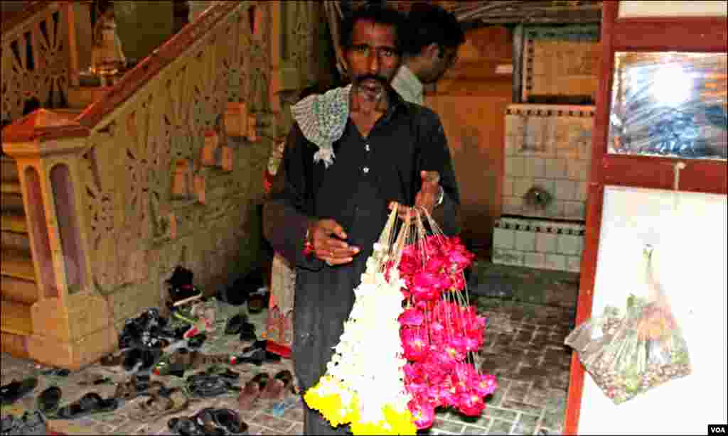 ہندوں کے مذہبی تہوار کے موقع پر مندر کے باہر ایک شخص پھول فروخت کررہاہے