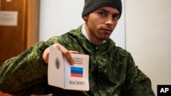 FILE - A young Russia-backed rebel shows a passport of self-proclaimed Luhansk Peoples Republic.