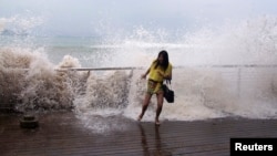 A woman reacts as a storm surge jumps a barrier on the shore as Typhoon Usagi approaches Shenzhen, Guangdong province, September 22, 2013.