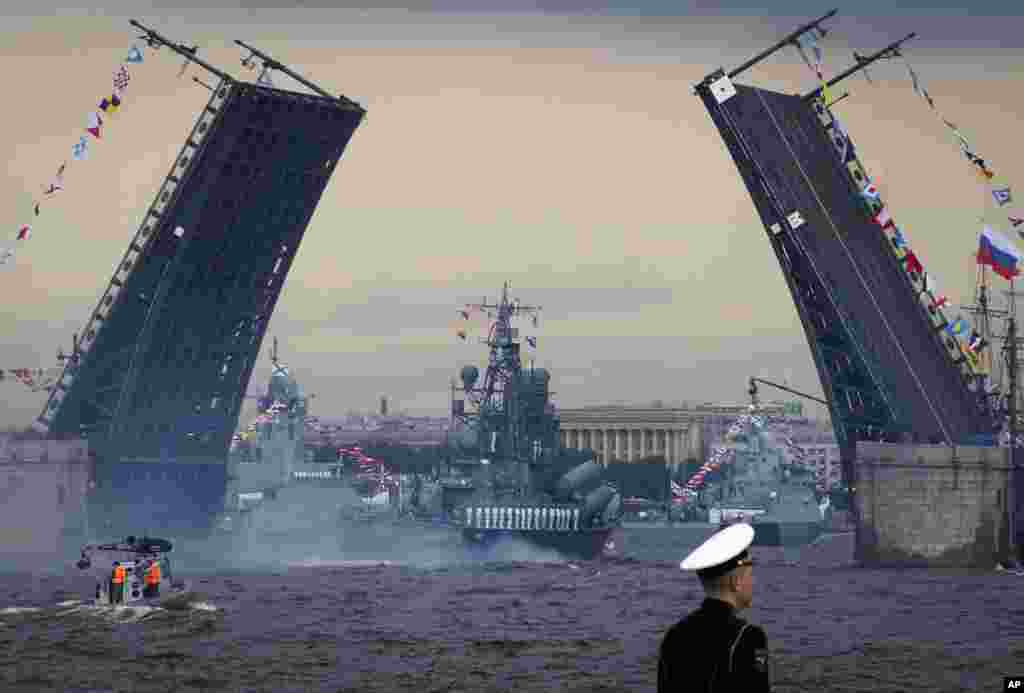 Sebuah kapal perang Rusia melewati jembatan Dvortsovy (Istana) yang menjulang di atas Sungai Neva selama parade Hari Angkatan Laut di kota St.Petersburg, Rusia.