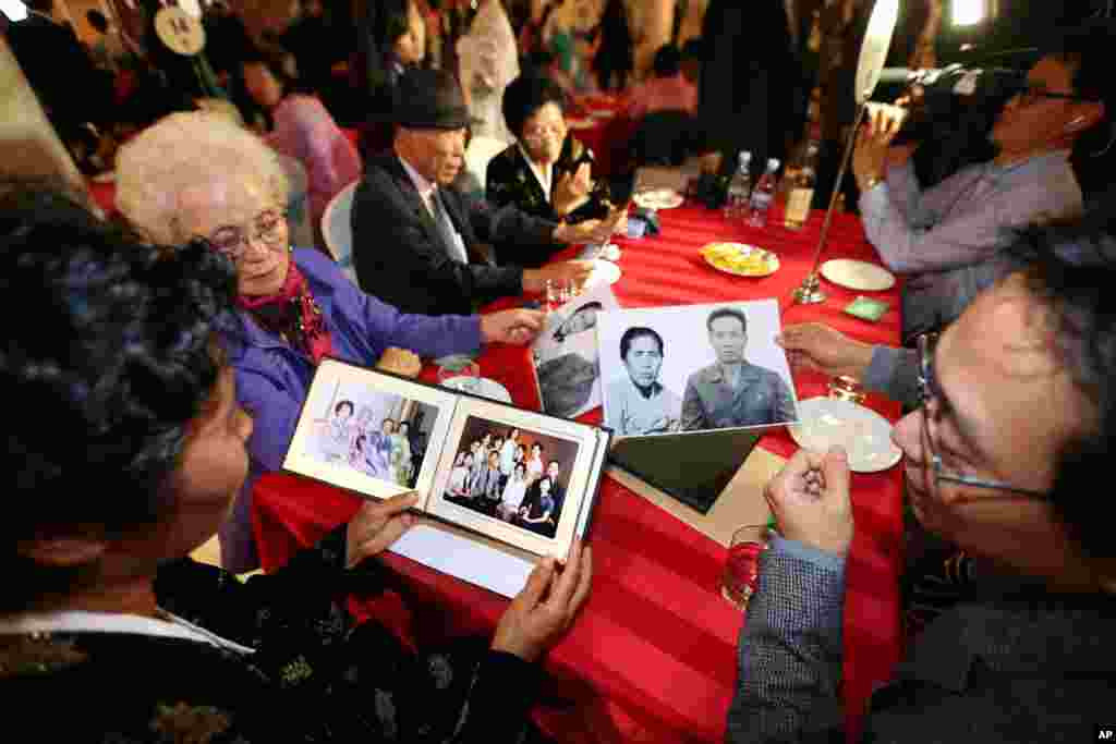 Family members from South and North Korea show family photos during the Separated Family Reunion Meeting at the Diamond Mountain resort in North Korea, Oct. 24, 2015.