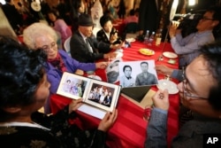 Family members from South Korea and North Korea show their family photos each others during the Separated Family Reunion Meeting at the Diamond Mountain resort in North Korea, Oct. 24, 2015.