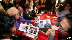 Family members from South Korea and North Korea show their family photos each others during the Separated Family Reunion Meeting at the Diamond Mountain resort in North Korea, Oct. 24, 2015. 
