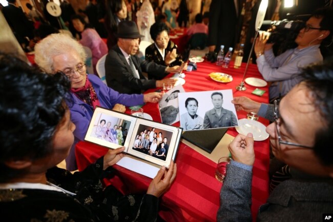 Family members from South Korea and North Korea show their family photos each others during the Separated Family Reunion Meeting at the Diamond Mountain resort in North Korea, Oct. 24, 2015.
