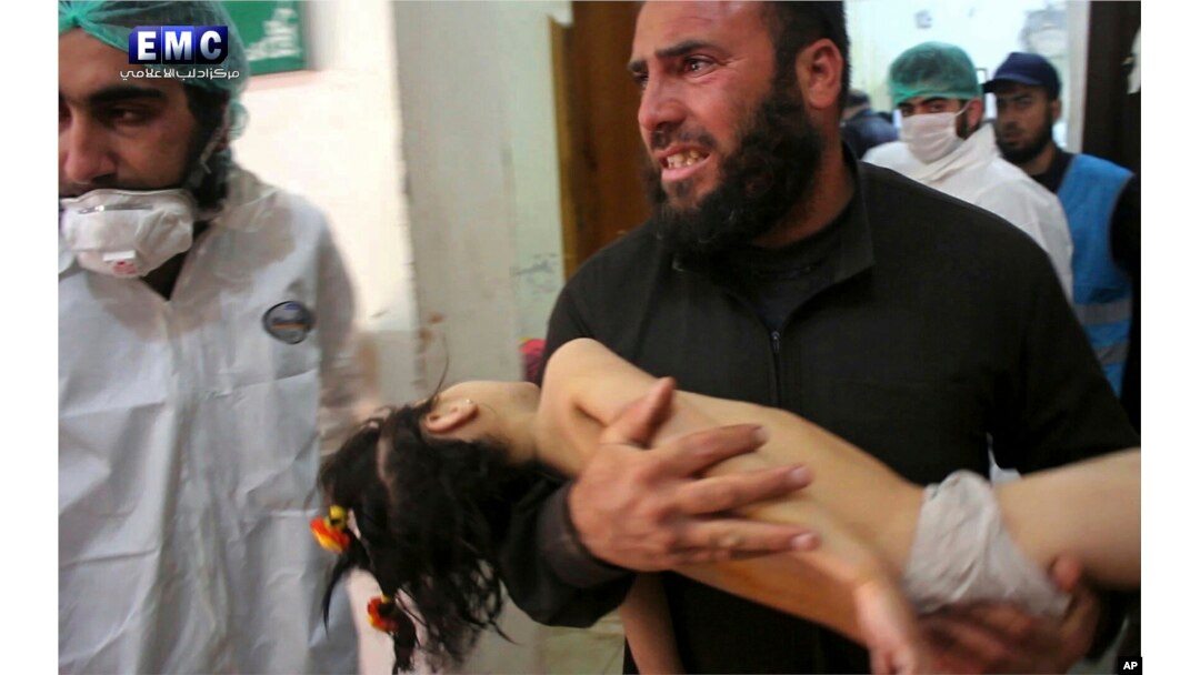 FILE - This April 4, 2017, photo provided by the Syrian anti-government activist group Edlib Media Center shows a man carrying a child following a suspected chemical attack at a makeshift hospital in the town of Khan Sheikhoun, Idlib province, Syria.