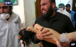 FILE - This April 4, 2017, photo provided by the Syrian anti-government activist group Edlib Media Center shows a man carrying a child following a suspected chemical attack at a makeshift hospital in the town of Khan Sheikhoun, Idlib province, Syria. Walid Moallem, Syria's foreign minister, told reporters April 6 that his country didn't use chemical weapons in the attack.