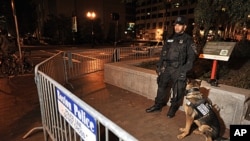 A police officer and dog guard stand behind barricades after police arrested people sleeping in an expansion of the Occupy Boston tent village on the Rose Kennedy Greenway in Boston, in the early morning hours, October 11, 2011.
