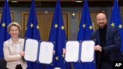 Predsednica Evropske komisije Ursula fon der Lajen i predsednik Evropskog saveta Šarl Mišel pokazuju potpisani trgovinski sporazum EU i Britanije u sedištu Evropskog saveta u Briselu.