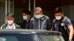 Police officers escort Cheung Kim-hung, right, CEO and Executive Director of Next Digital Ltd at Apple Daily headquarters in Hong Kong, Thursday, June 17, 2021. (AP Photo/Kin Cheung)