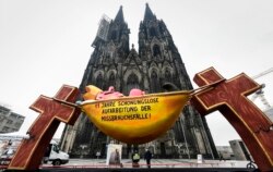 Kendaraan hias karnaval yang menggambarkan Kardinal yang sedang tidur, bertuliskan '11 tahun tanpa henti pemrosesan kasus pelecehan' dipasang di depan Katedral Cologne untuk memprotes Gereja Katolik di Cologne, Jerman, Kamis, 18 Maret 2021.