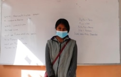 Abelina Choque stands inside her classroom next to her work, left, she wrote out on a dry erase board, during an Uru language lesson, in the Urus del Lago Poopo indigenous community, in Punaca, Bolivia, Monday, May 24, 2021.