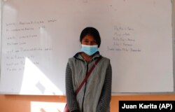 Abelina Choque stands inside her classroom next to her work, left, she wrote out on a dry erase board, during an Uru language lesson, in the Urus del Lago Poopo indigenous community, in Punaca, Bolivia, Monday, May 24, 2021.
