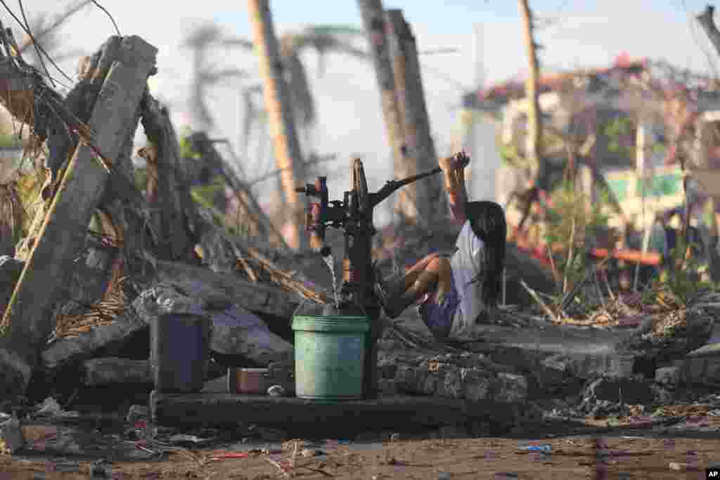 A young typhoon survivor fetches water from a hand pump at typhoon-ravaged Tolosa town, Leyte province, central Philippines. 