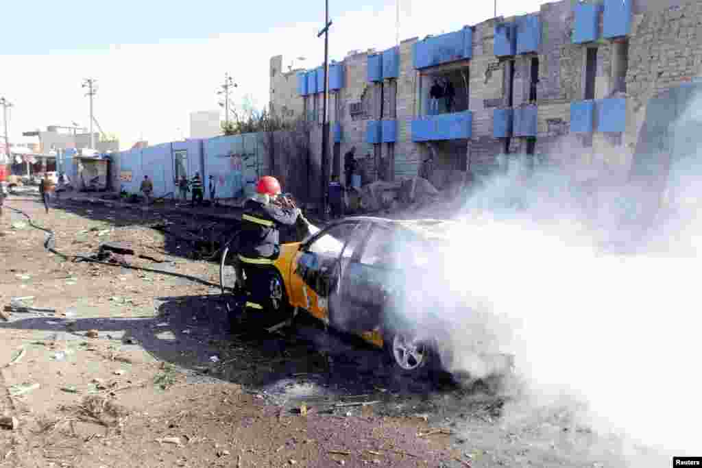 A firefighter hoses down a destroyed vehicle at the site of bomb attack in Kirkuk, Jan. 7, 2014. 