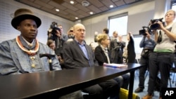 Friends of the Earth campaign leader Geert Ritsema (2 L), and plaintiff Eric Dooh (L) wait for the start of the ruling in the court case of Nigerian farmers against Shell, in The Hague, Netherlands, January 30, 2013.