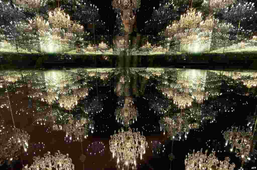 A gallery assistant poses for a photograph with an art installation entitled &quot;Chandelier of Grief&quot;, 2016, by Japanese artist Yayoi Kusama, at the Victoria Miro gallery in London.