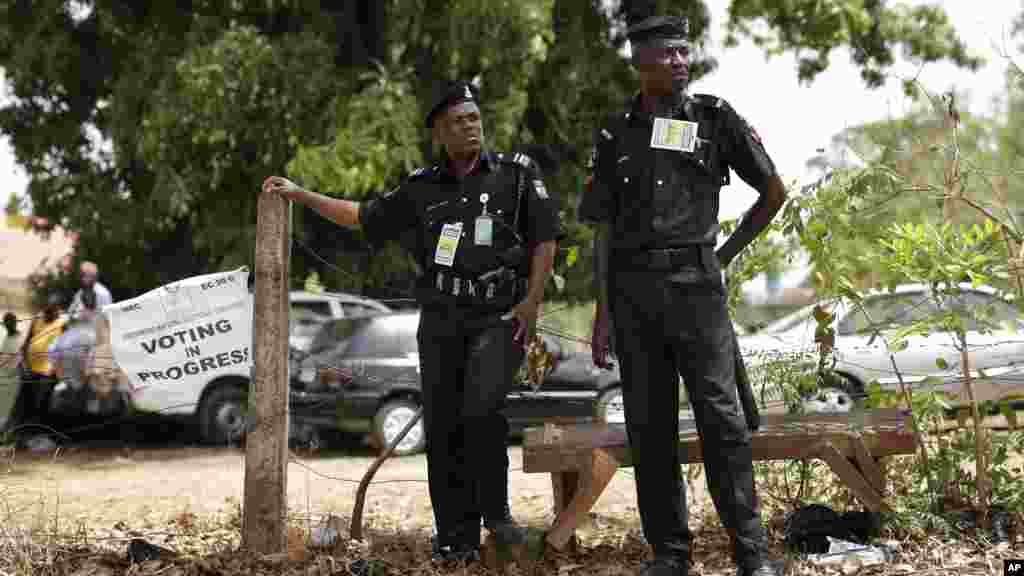 Des policiers nigérians surveillent alors que les électeurs en queue attendent de voter à Kaduna, au Nigeria samedi 28 mars 2015.