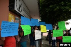 Migrantes de diferentes nacionalidades sostienen pancartas durante una protesta contra la larga espera para recibir documentos para legalizar la estadía y evitar que las Guardias Nacionales detengan a los migrantes en México, fuera de la oficina de la Comisión Nacional de Derechos Humanos en Tapachula, México, el 20 de junio de 2019.