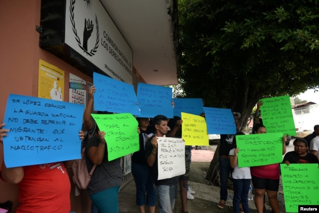 Migrantes de diferentes nacionalidades sostienen pancartas durante una protesta contra la larga espera para recibir documentos para legalizar la estadía y evitar que las Guardias Nacionales detengan a los migrantes en México, fuera de la oficina de la Comisión Nacional de Derechos Humanos en Tapachula, México, el 20 de junio de 2019.